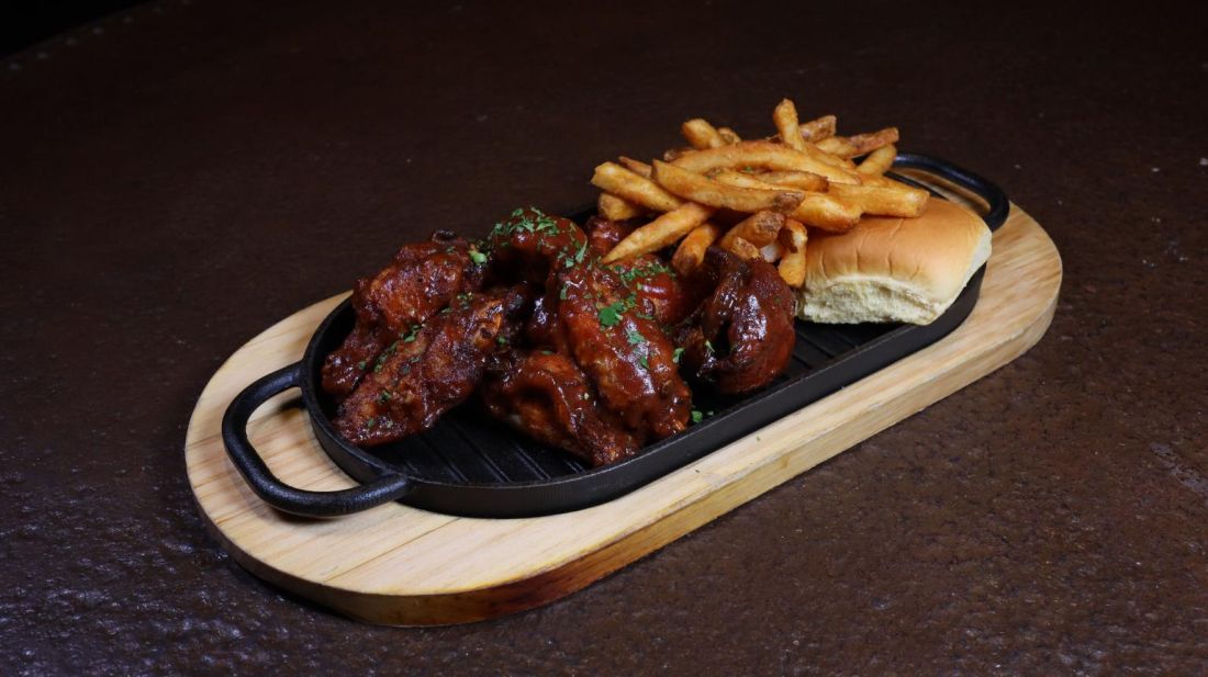 Glazed chicken wings with fries and a bun