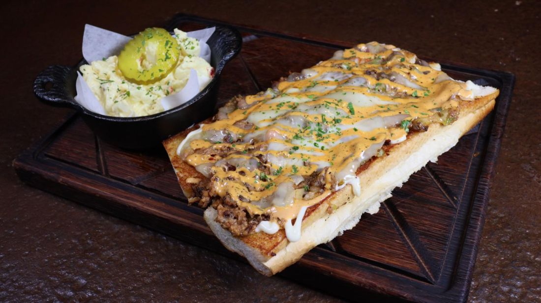 Cheesesteak-style sandwich on toasted bread with a side